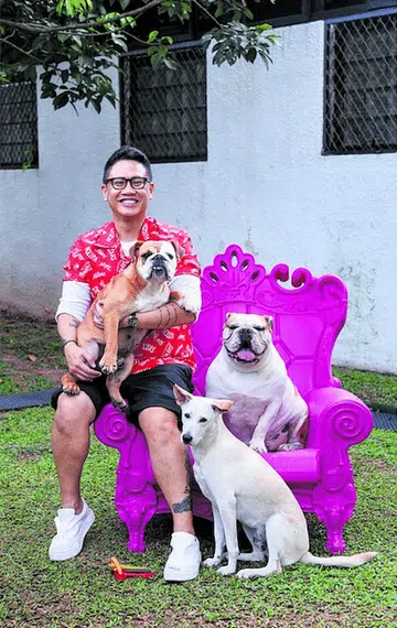 Art gallery co-owner Kenneth Tan poses with his 3 dogs in the yard of his semi-detached house off Yio Chu Kang Road.