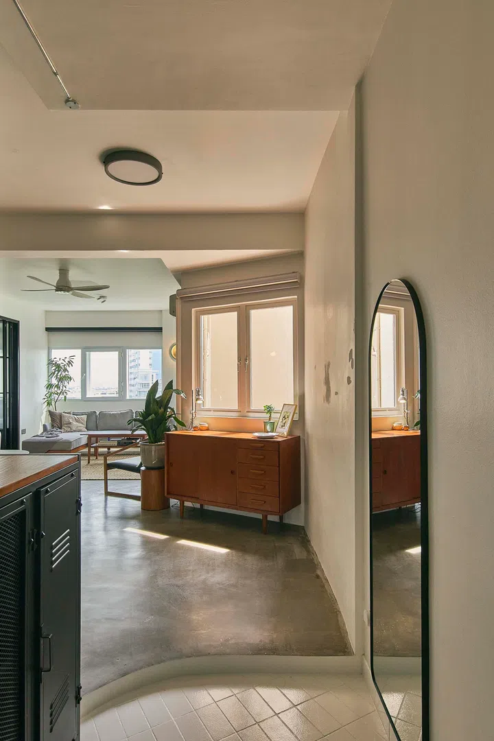 The entrance foyer is a bright and minimalist space simply furnished with a shoe cabinet and a wall mirror. 