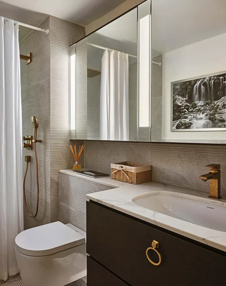 Mirrored cabinets visually enlarge this monochromatic bathroom.