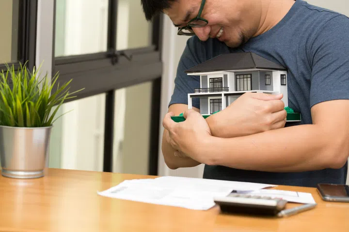 Asian man smiling and hugging a dream home and calculate to buy a house dreaming at his future.