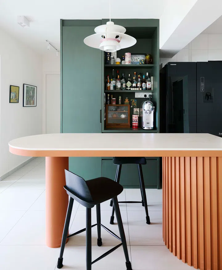 The kitchen island with its vibrant orange fluted panels and contrasting green cabinetry, inspired by board game cafés.