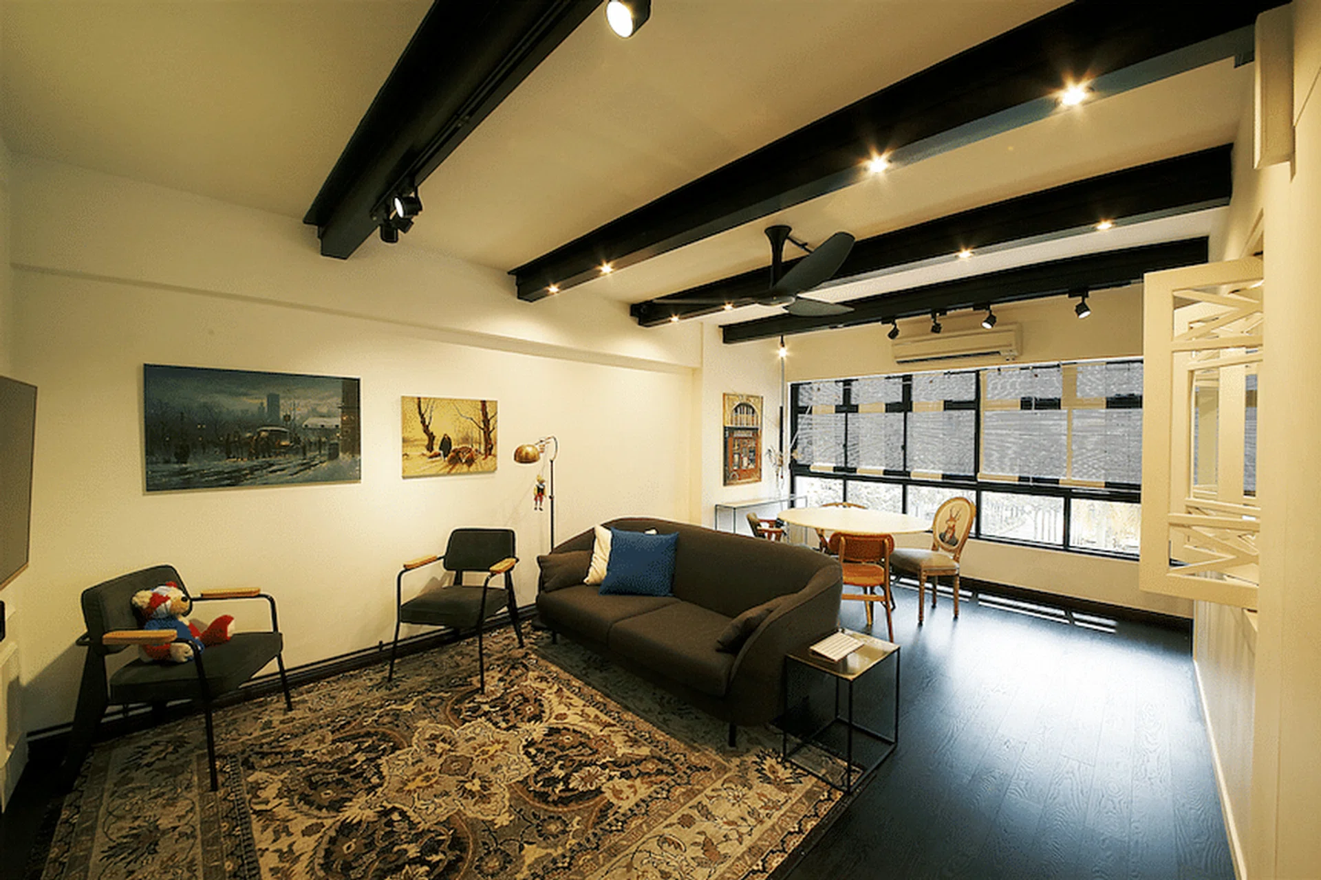 The white walls, dark engineered wood flooring and exposed ceiling beams in the living room reflect the coupleʼs love for the colonial black-and-white style.