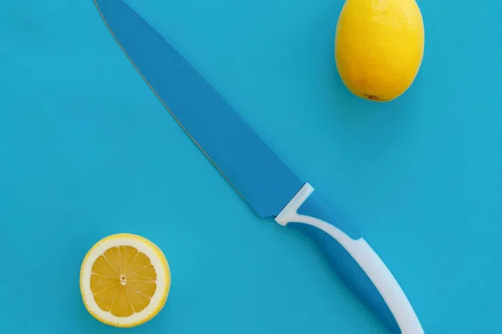 Lemon and knife on blue background. Minimal summer concept.