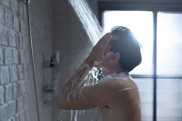 Handsome asian guy Taking a shower in the bathroom