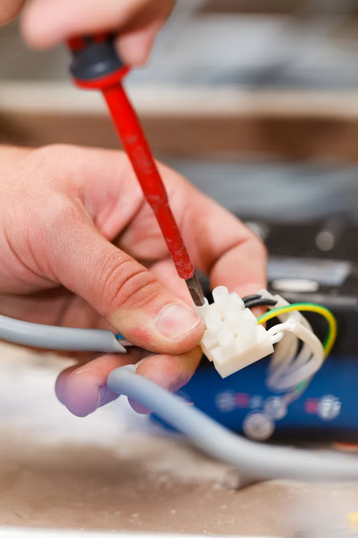 Handy man electrician assembling light working with cables.