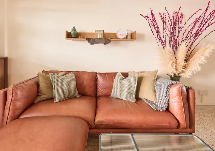 A full-grain leather sofa anchors the living area with warmth and texture, complemented by soft textiles and subtle hints of Chinese décor.