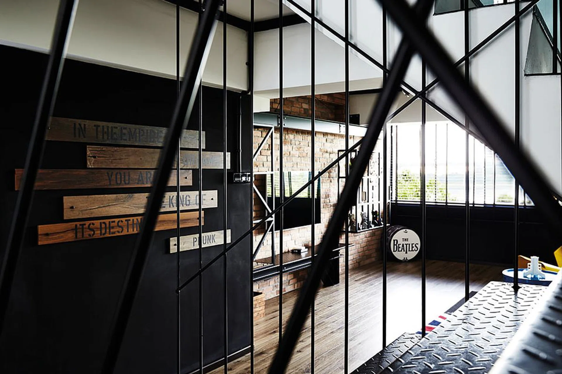 The interior designer balanced the warm wood floors and red brick wall with hints of cool black and metal in this 3-bedroom HDB Maisonette.
