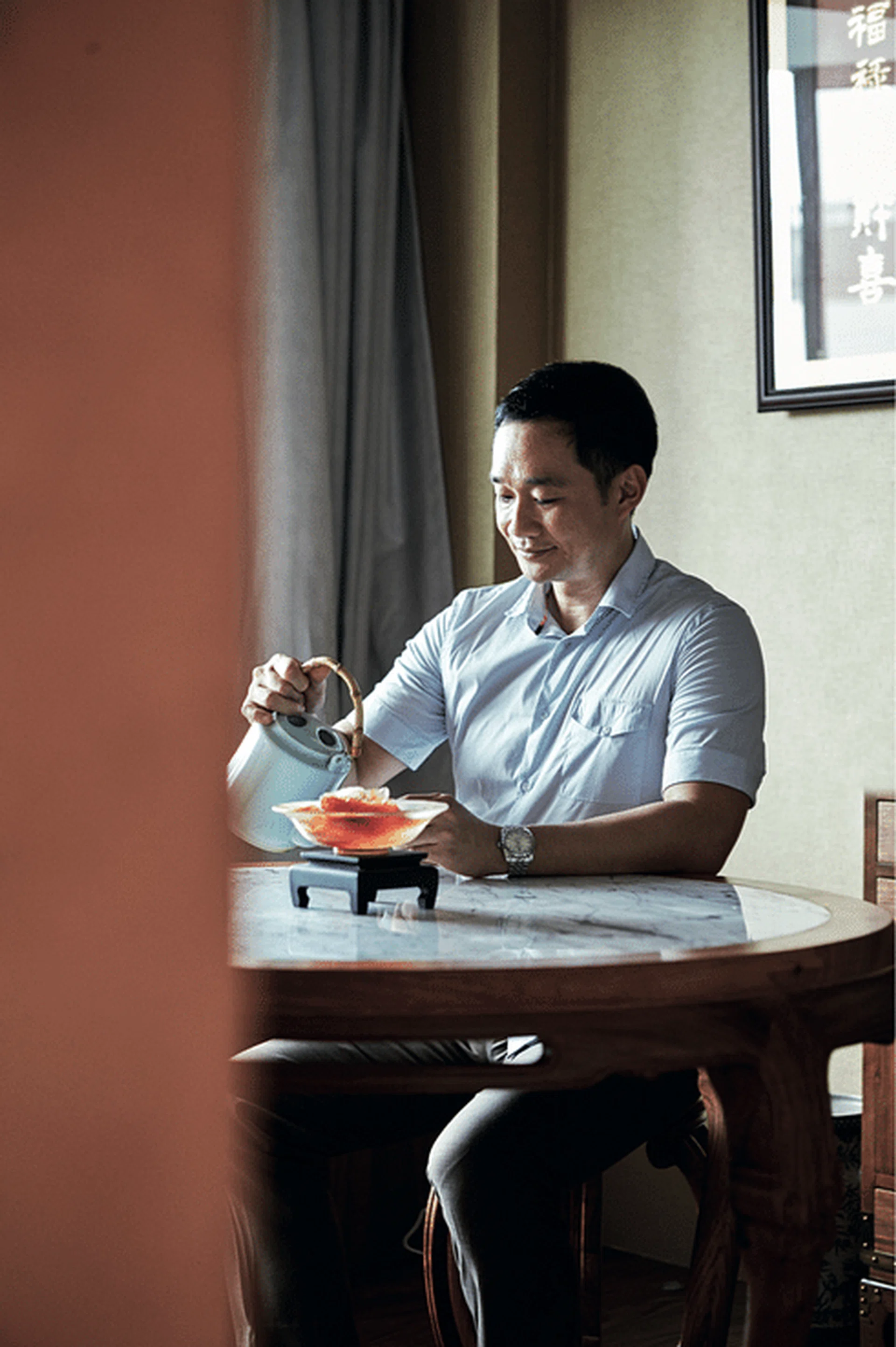 A former banker, Wilfred Leu found his calling as a fengshui practitioner after a debilitating financial crisis in 2008, posing with a pot and cup of tea at his home's dining table.