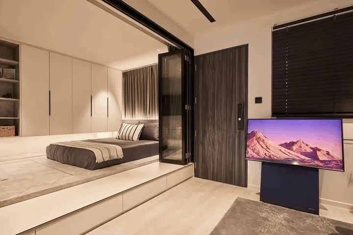 Aiken Chia's bedroom, located at the side of the entrance, is on an elevated platform separated from the living room by black-framed accordion glass doors and curtains.