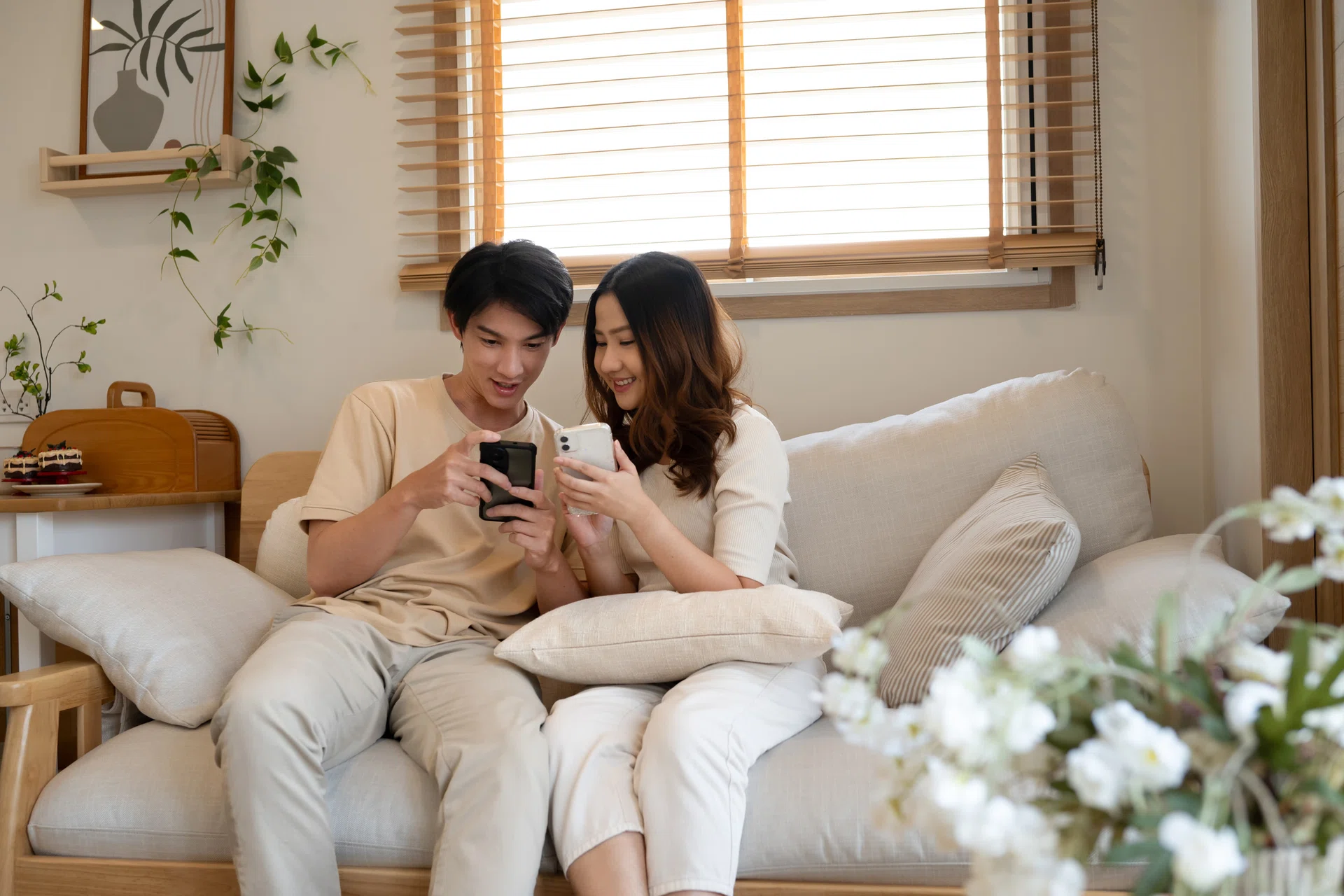 Happy young couple sharing moments on their smartphones at home.