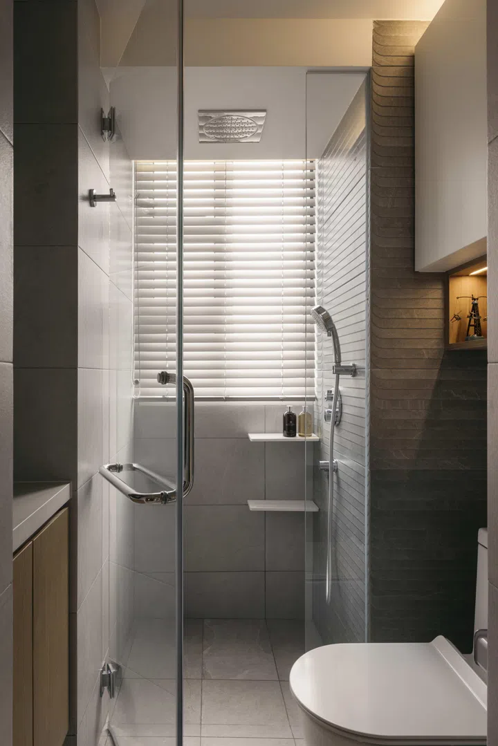 The common bathroom is kept compact and efficient, with a glass-enclosed shower and light-toned finishes that prioritise everyday use.