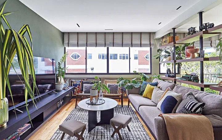 The colours and materials in the living area complement that of the dining room. Walnut-framed sofa and armchairs are paired with a dark green wall that invokes nature