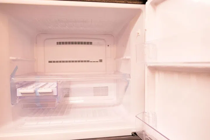 Open empty new white refrigerator inside fridge with shelves.
