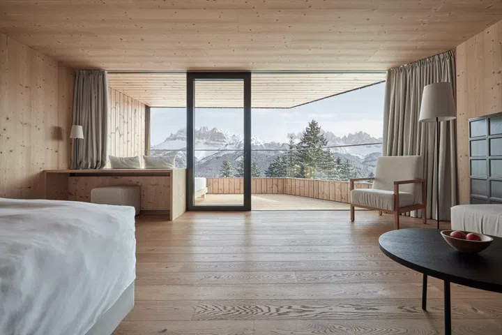 The FORESTIS tower suite features floor-to-ceiling glass walls with unobstructed panoramic views of the Dolomites.