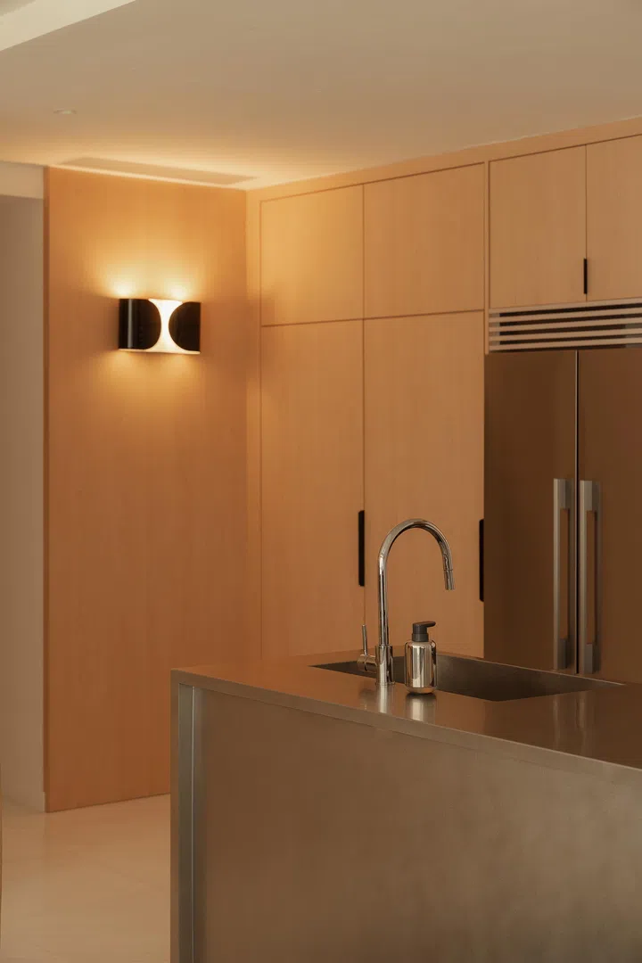 Warm timber cabinetry and a brushed steel island lend the kitchen a refined, sculptural presence.