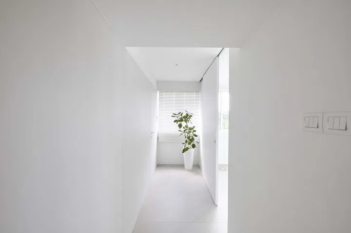 Stark, minimal, all white corridor with a planter at the end.