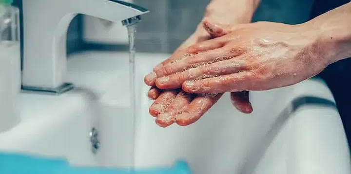 A pair of soapy washing hands by the sink tap. Photo 123RF