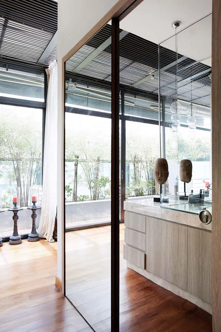 A host of mirrored surfaces in the master bedroom reflects the light entering from the full-height windows, lending a resort-like feel to the space.