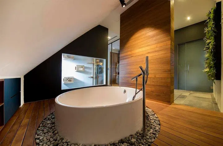 This open-concept bathroom in this luxurious bungalow has a round tub; the space resembles a Japanese onsen. Interior design by 82.