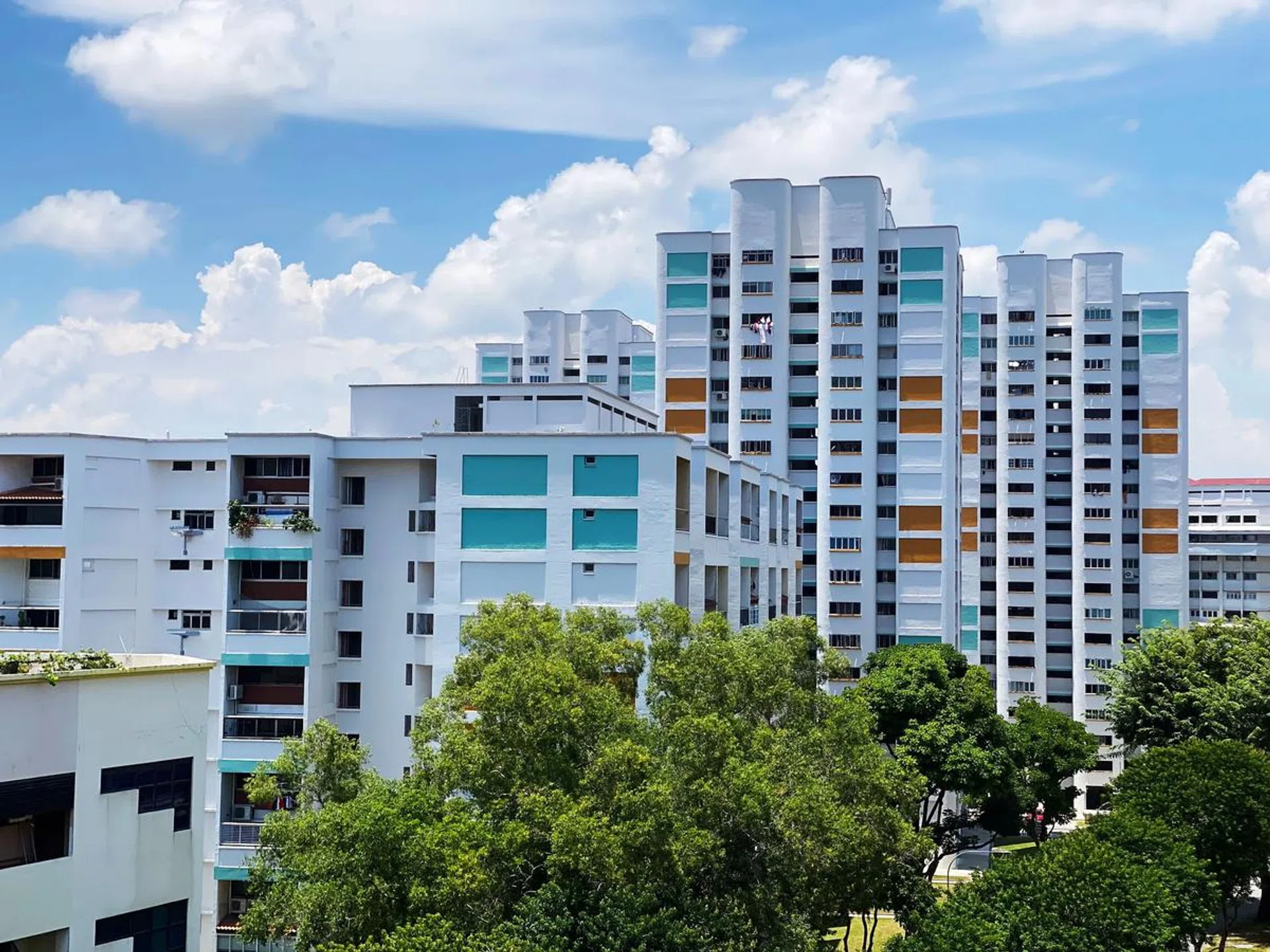 Distant view of Singapore's HDB housing blocks under cloudy blue sky. Photo 123RF