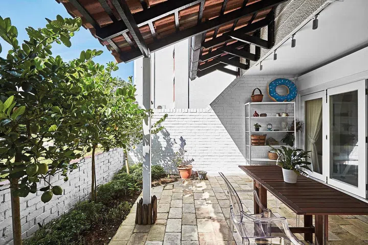 A generously-sized terrace with an alfresco dining set-up, bordered by three lemon trees weighed down with fruit.