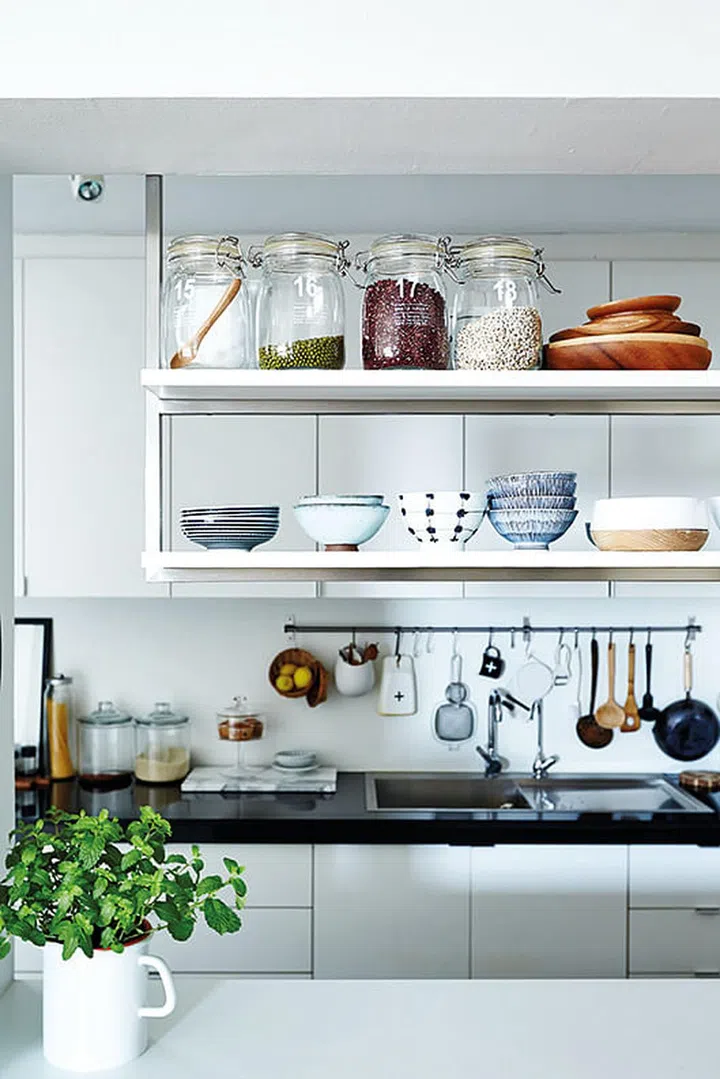 Some ingredients and Japanese crockery are displayed on this suspended kitchen shelf. The labels on the jars were designed by the homeowner himself.
