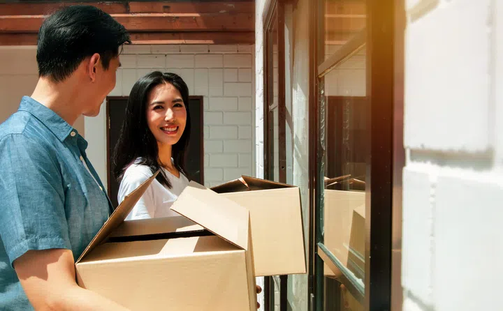 Young couples planning their families, moving into a new home family happiness and living together. Asian couple brings home accessories boxes to the door of their family’s new home with happy smile.