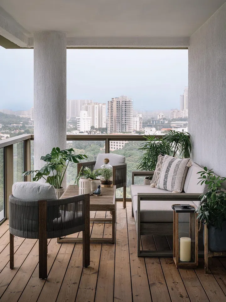 Wood deck and outdoor lounge sofas in the terrace of a 2-bedroom apartment in Parsi, Mumbai.