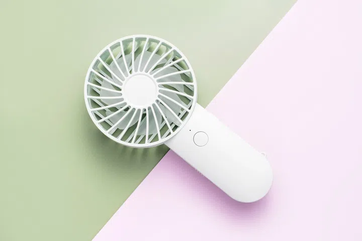 Small fan on green and pink background close up.