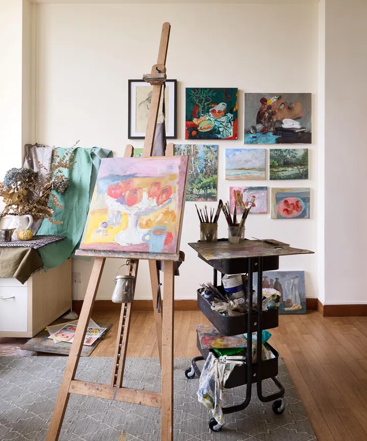 A sunlit studio space with artworks displayed on the walls, showcasing a working artist’s creative corner.