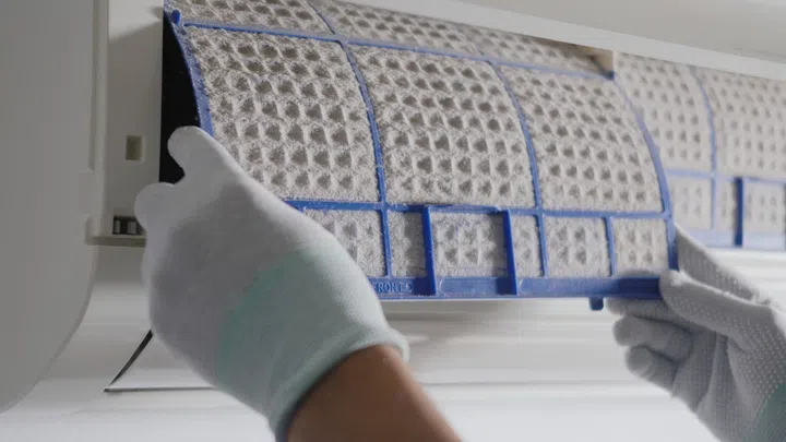Person removing air conditioner filter, Hand of technician man working pulling dusty filter from air conditioner to cleaning in the room at home