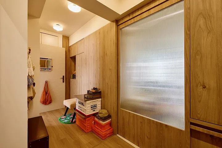 With the sliding door shut, the foyer reads as a self-contained buffer zone—warm, compact and visually distinct from the main living areas.