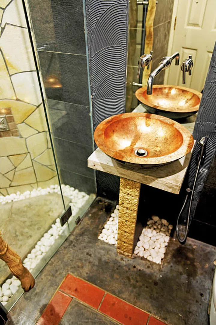The guest bathroom makes a strong bucolic statement with cement and pebble flooring, Balinese tiles and copper sink. Interior design by Ethnic Fusion ID