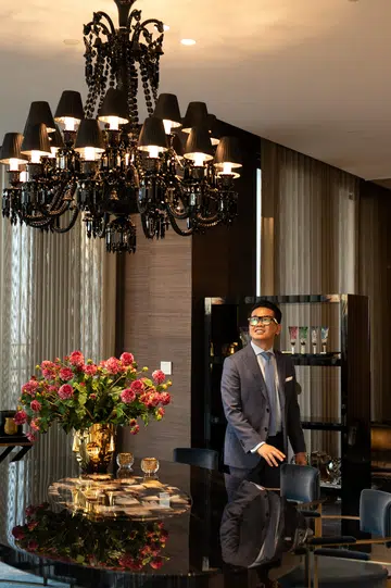 Interior designer Quach Thai Cong posing in a glamorous dining room.