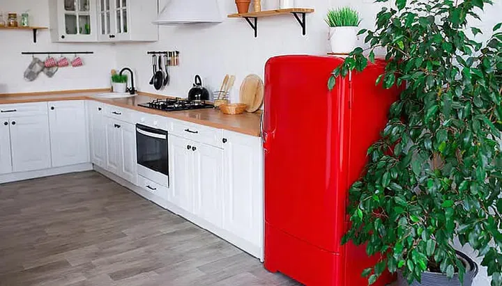 A red fridge in an all white and wood kitchen. Photo 123RF