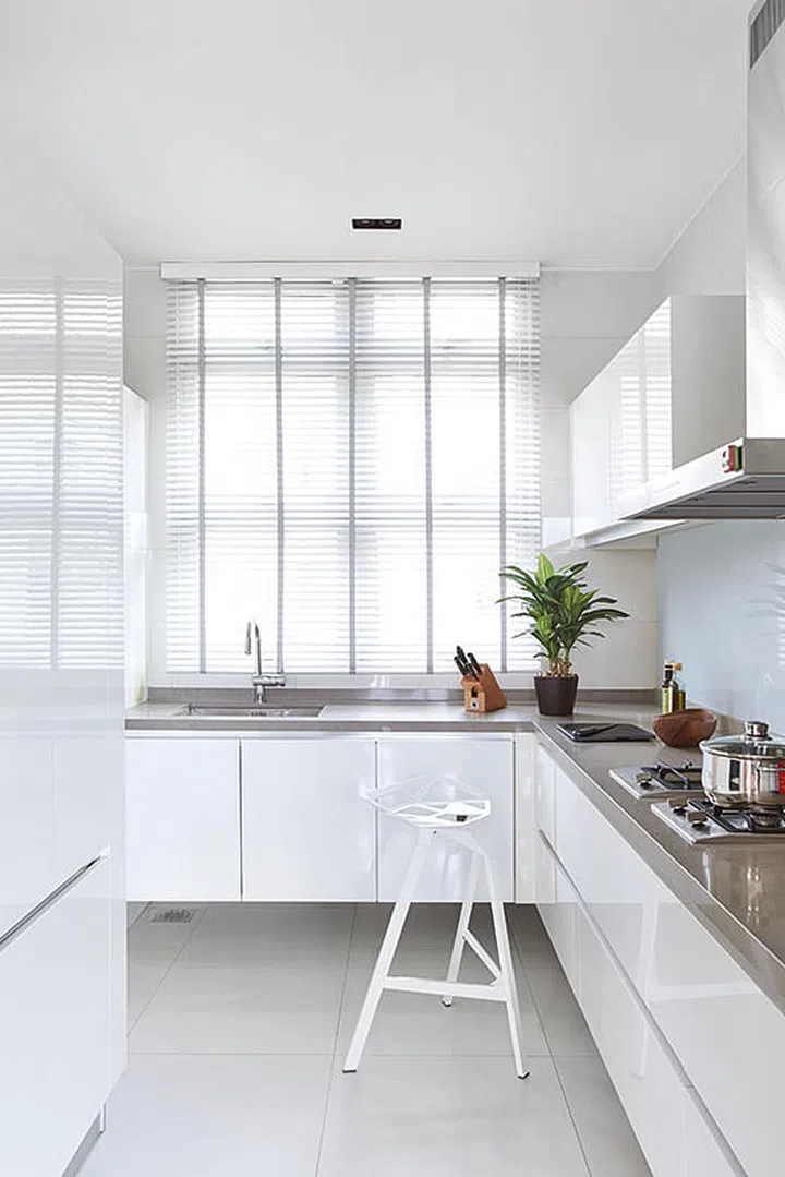 The gleaming white and steel kitchen, which comes with plenty of under-the-counter storage, is a picture of modernity in William Png's white and wood 3-bedroom condominium off Orchard Road.