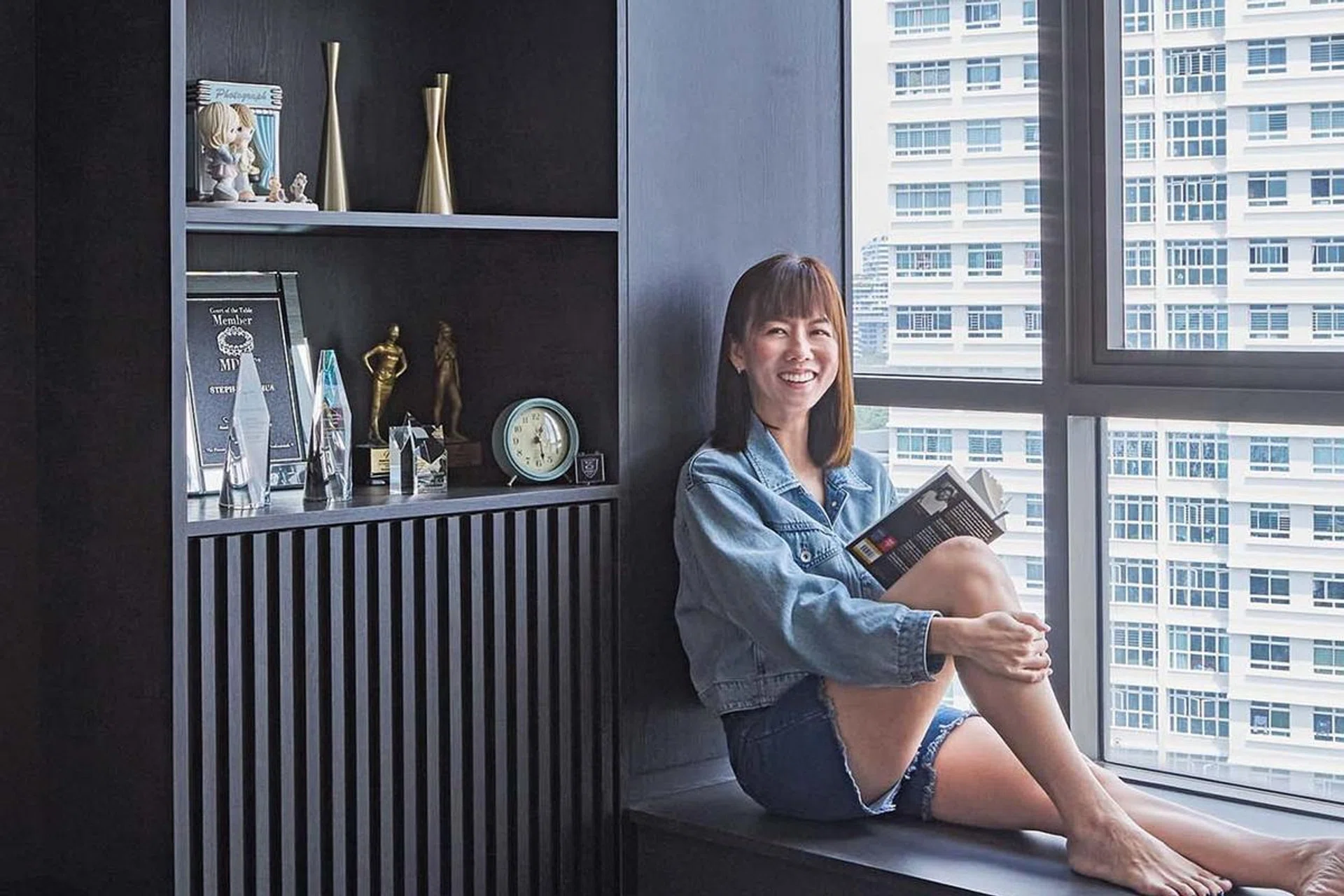 Stephanie Chua, a female master financial consultant strikes a pose on the bay window of her 2-room condo in Telok Blangah