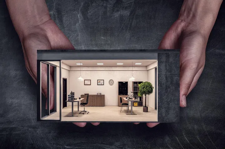 Businessman in office interior with house model in hands. Mixed media