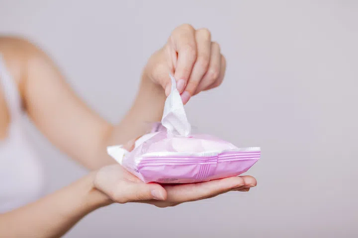 Woman use package of wet wipes and take one wipe