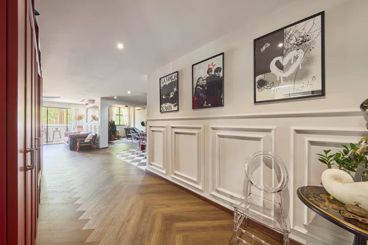 Classical wall mouldings line the entry corridor, layered with artworks created by the homeowners, offering an immediate glimpse into the home’s personal and artistic direction.