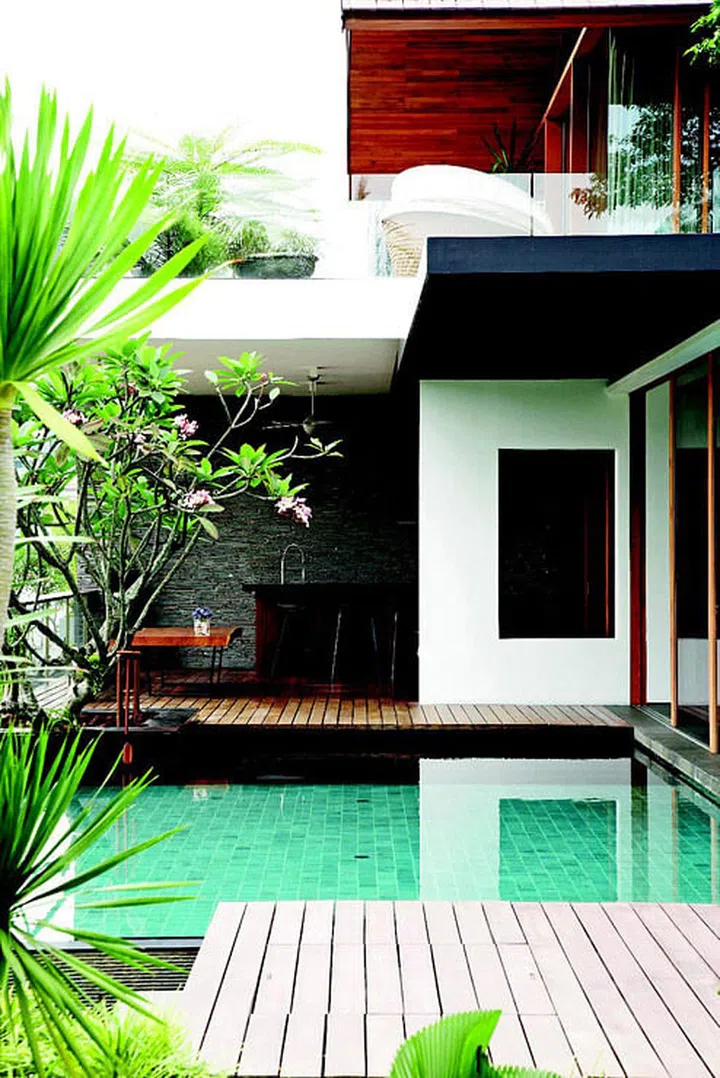 The view from the side of the home shows the outdoor dining area on the first storey and the study room on the second storey in this 2-storey bungalow in Sentosa Cove.