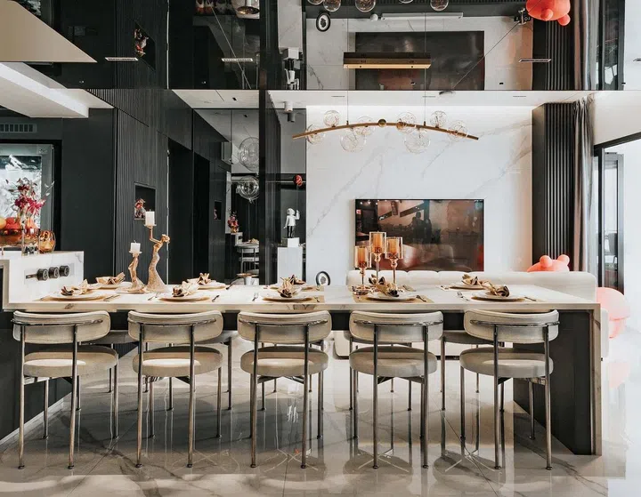 A luxurious living and dining room with a marble TV wall and black accents