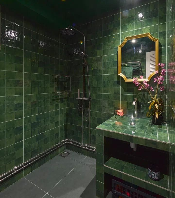 The second bathroom shifts to deep green tiles, creating a distinct mood while maintaining the same immersive approach.