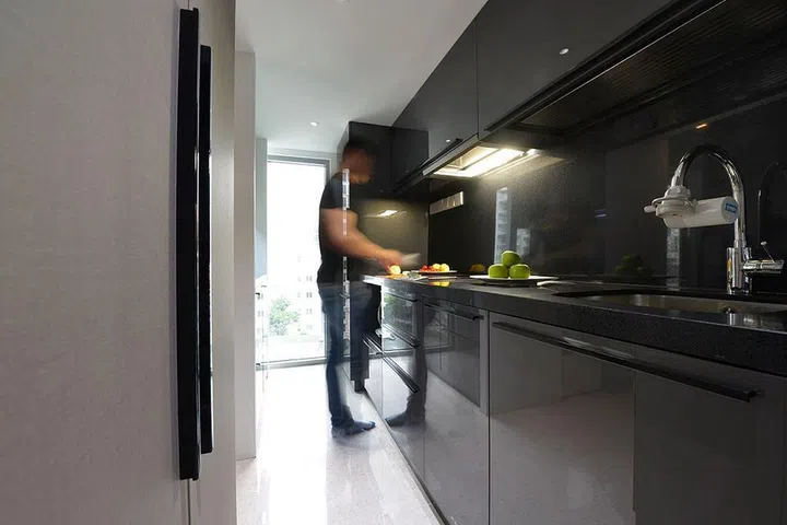 Dark kitchen with a small induction hob in a family of 3's 840 sq ft mini condominium in River Valley, designed by interior designer Kelvin Bing.