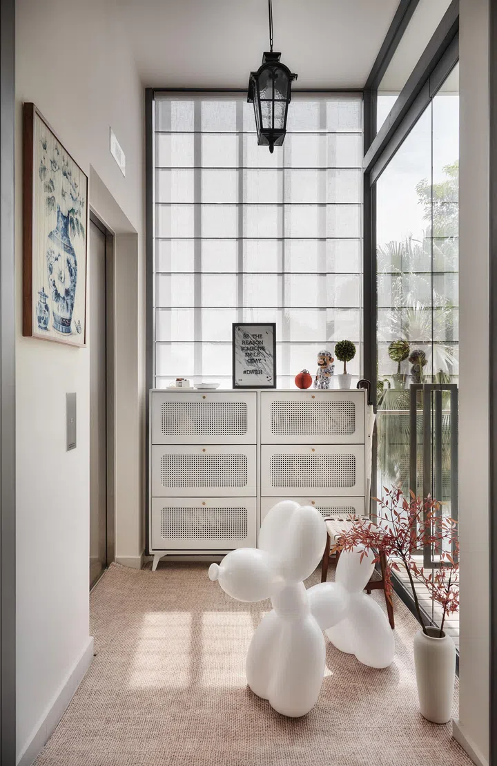 The serene entryway hints at the home’s tactile theme, blending rattan textures, natural light, and playful personal touches.