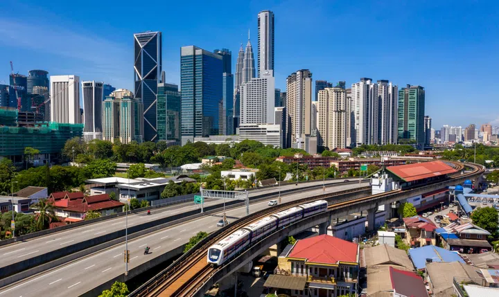 KUALA LUMPUR, MALAYSIA - FEBRUARY 28, 2020 : Kuala lumpur skyline with view of LRT train, highways road and blue sky background.