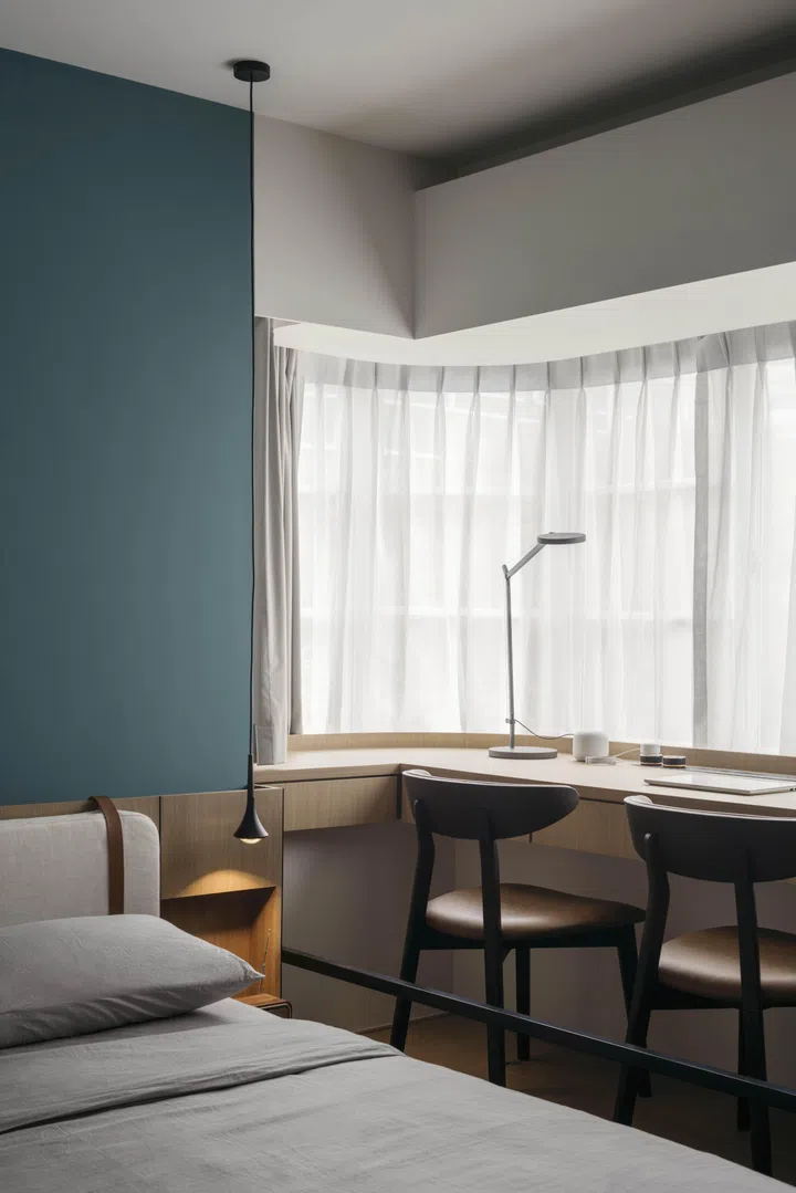 A long writing desk by the window creates a quiet workspace within the master bedroom.