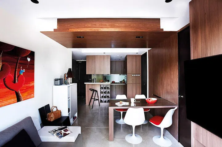 A painting from Ode to Art adds a pop of colour to the woody hues of the apartment, as do the Tulip chairs from Dream Interiors. Sofa from B&W. Cabinet and barstool from Xtra Park Mall.