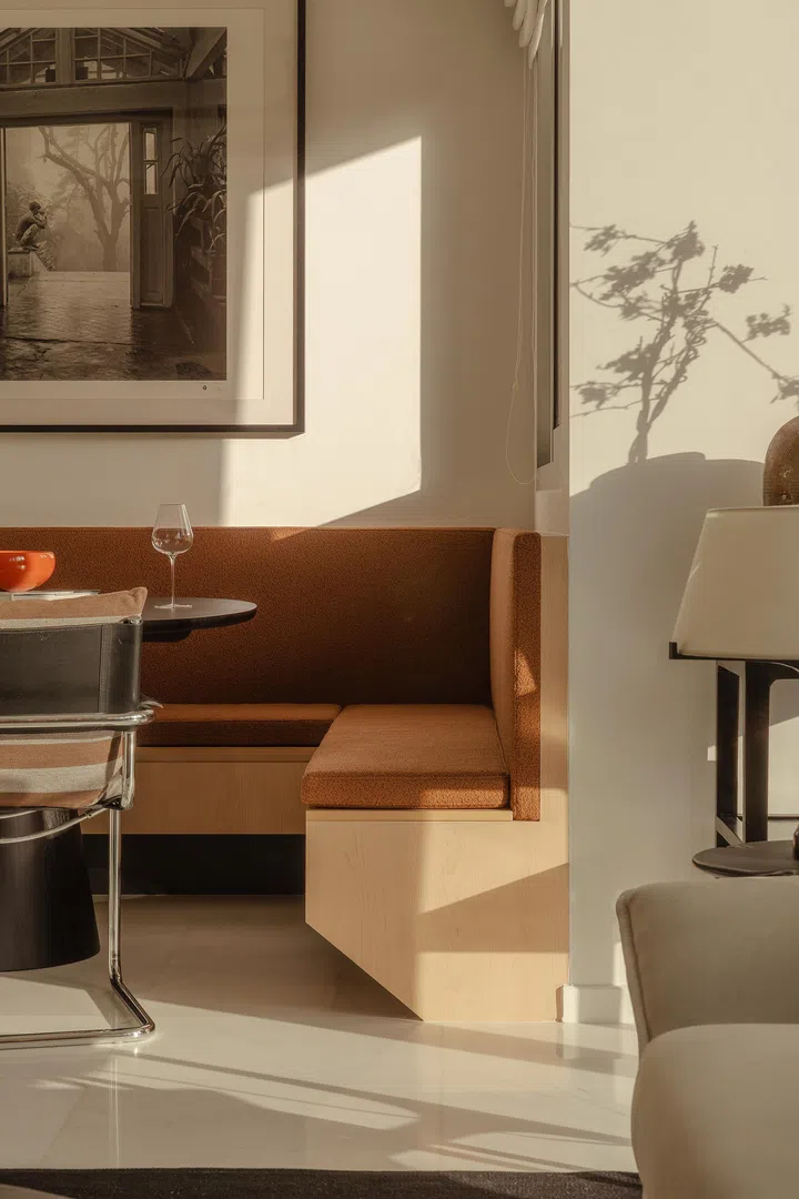 Soft afternoon light catches the textured upholstery and framed photograph above the dining nook.