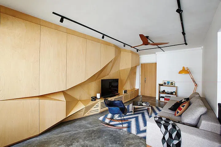 The eye-catching feature panel in the living area, which has a faceted surface that resembles origami folds, also hides an overhead beam.